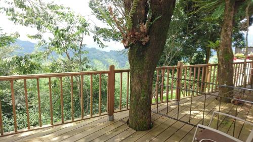 a wooden deck with a tree and a fence at SunSweet House in Fanlu
