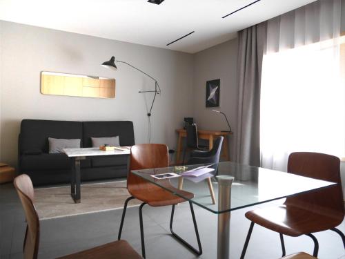 uma sala de estar com uma mesa de vidro e cadeiras em Le Chat Qui Dort - Suites em Lille