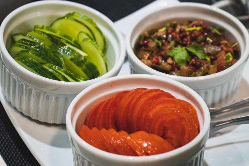 three bowls of food on a table with vegetables at Concept Design Hostel & Suites in Foz do Iguaçu