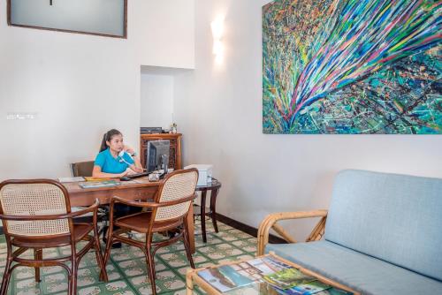 a woman sitting at a table in a room at Areca Hotel Penang in George Town