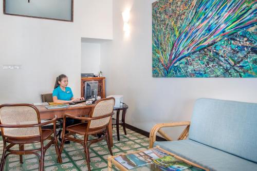 a woman sitting at a table in a room at Areca Hotel Penang in George Town