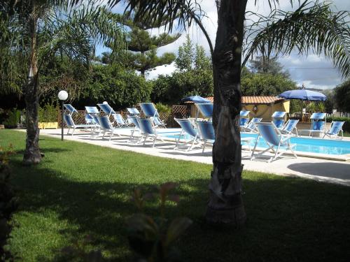 a row of lounge chairs and a swimming pool at Hotel La Fattoria Sul Mare in Capo Vaticano