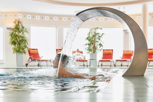 a boy swimming in a pool with a fountain at ROBINSON AMADÉ in Kleinarl