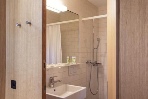 a bathroom with a sink and a shower with a mirror at Hotel Arenenberg in Salenstein