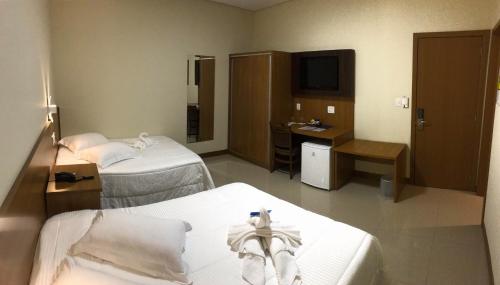 a hotel room with two beds and a television at Ipê Palace Hotel in Adamantina