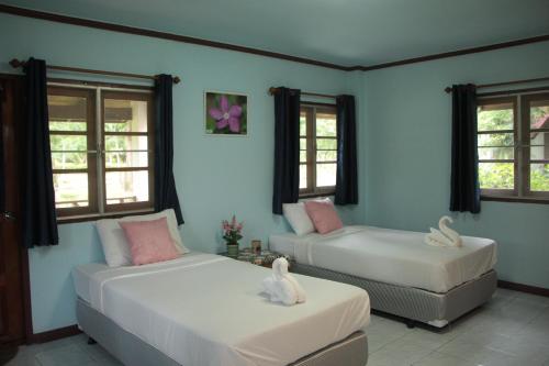 a bedroom with two beds and windows with swans on them at River Kwai Park & Resort in Chongsadao