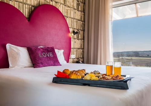 a tray of food on a bed with two glasses of beer at Lisotel - Hotel & Spa in Leiria