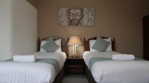 two beds in a hotel room with a head on the wall at The Broadway Hotel in Llandudno