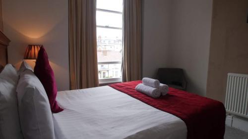 a bedroom with a bed with a teddy bear on it at The Broadway Hotel in Llandudno