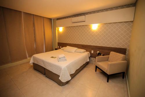 a hotel room with a bed and a chair at Alfa Hotel Teresina in Teresina