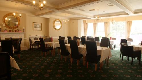 a dining room with tables and chairs and a mirror at The Broadway Hotel in Llandudno