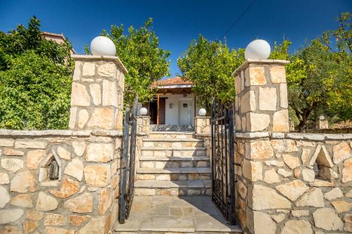 a stone fence with a gate in front of a house at Aggerikos Relax House in Ayios Kirikos