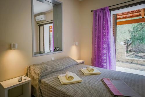 a bedroom with a bed and a window with purple curtains at Aggerikos Relax House in Ayios Kirikos