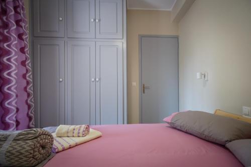 a bedroom with a pink bed with white cabinets at Aggerikos Relax House in Ayios Kirikos