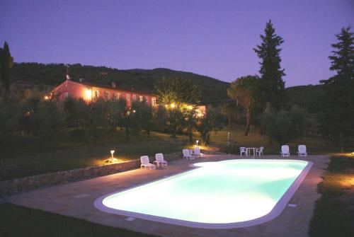 a swimming pool at night with chairs and a house at B & B San Jacopo in Santomato 