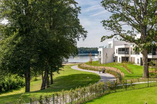 a path leading to a white building with a lake in the background at Golden Lakes Hotel in Boussu-lez-Walcourt