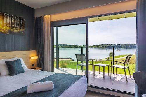 a bedroom with a bed and a balcony with a view at Golden Lakes Hotel in Boussu-lez-Walcourt