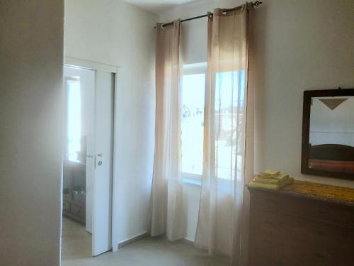 Habitación con ventana con cortinas y espejo. en Casette sul Porto en Isquia