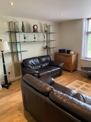 a living room with a leather couch and shelves at Lake Lounge Rooms in Littleborough
