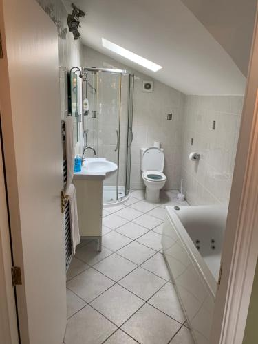 a bathroom with a tub and a toilet and a sink at Lake Lounge Rooms in Littleborough