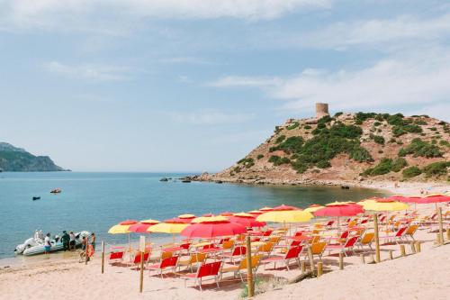 a beach with many chairs and umbrellas on it at Villaggio Camping Torre Del Porticciolo in Porto Conte