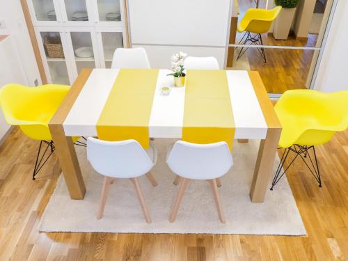 a dining room table with yellow chairs around it at Apartman Delux Adda in Zagreb