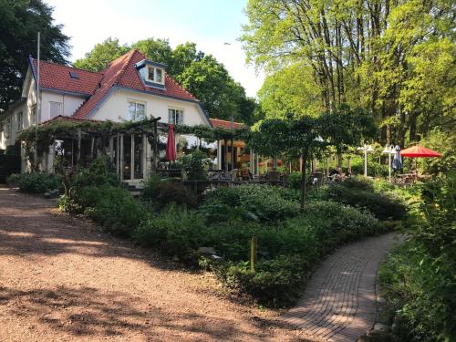 a house with a garden in front of a road at Natuurpark Hoefbos Boshuisje Veluwe in Otterlo
