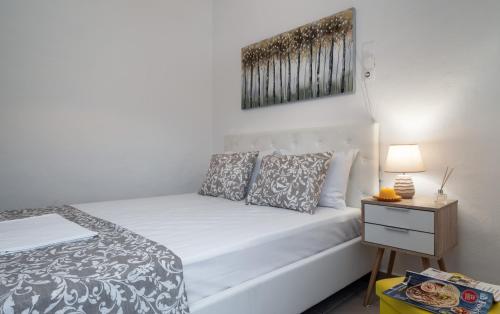 a bedroom with a white bed and a night stand at The Junction Appartment in Agia Galini