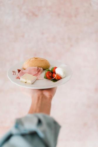 a hand holding a plate with a sandwich and cheese at Regina Teodolinda Suites in Laglio