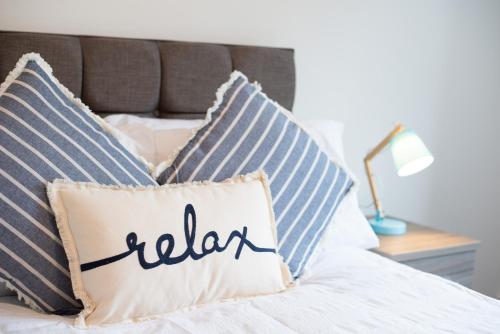 a pillow with the word relax sits on a bed at Large 4BR House Near Retail Parks & M4 in Swansea