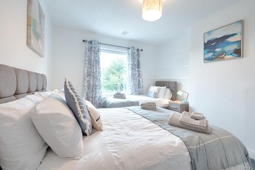 a bedroom with a large white bed and a window at Large 4BR House Near Retail Parks & M4 in Swansea