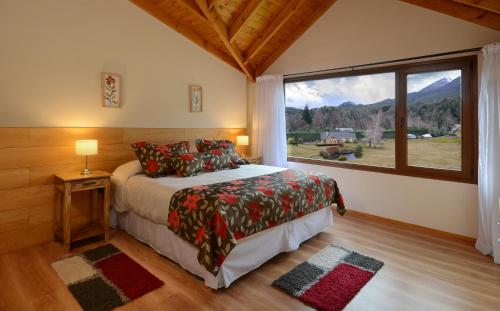 a bedroom with a bed and a large window at La Estancia Cabañas in Villa La Angostura