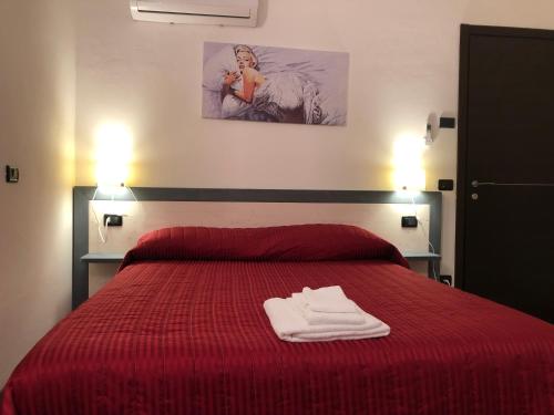 a bedroom with a red bed with two towels on it at La Casa di Anna in Delebio