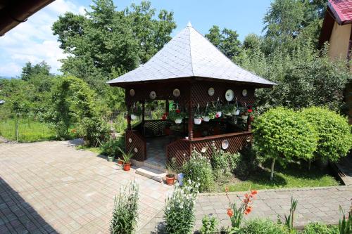 a wooden gazebo with a roof in a garden at Pensiunea Criveanu in Horezu