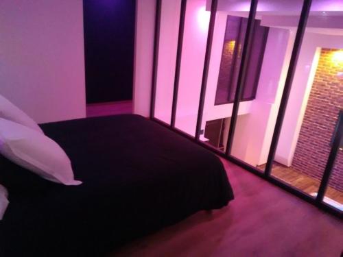 ein Schlafzimmer mit einem Bett und einem Fenster mit violetten Lichtern in der Unterkunft magnifique loft avec jacuzzi et sauna privatif in Ferrière-la-Grande