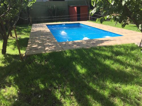 een zwembad in een tuin met groen gras bij Cabaña Colibri in San Alfonso