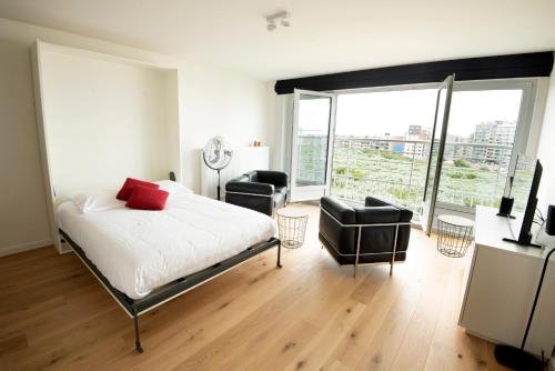 a bedroom with a bed and two chairs and a large window at Into the Sea in Middelkerke