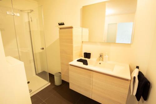 a white bathroom with a sink and a shower at Into the Sea in Middelkerke