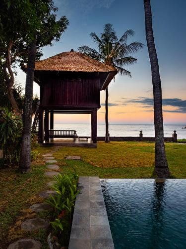 a gazebo with a bench next to the ocean at Villa Cantik in Lovina