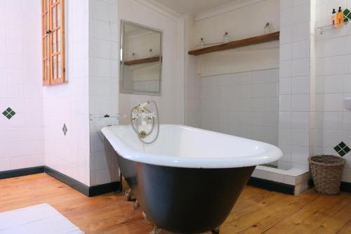 a bath tub in a bathroom with white tiles at Amber Light Wilderness Beach Cottage in Wilderness