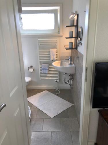 uma casa de banho com um lavatório, um WC e uma janela. em Bungalow 3 em Wyk auf Föhr