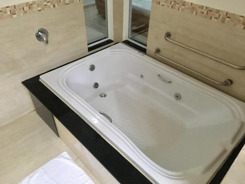 a white bath tub in a bathroom with a window at Tennessee Motel ltda in Bragança Paulista