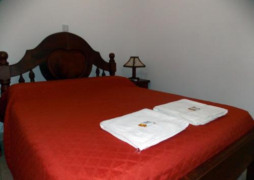 a bedroom with a red bed with white towels on it at Portal De Los Valles in Chicoana