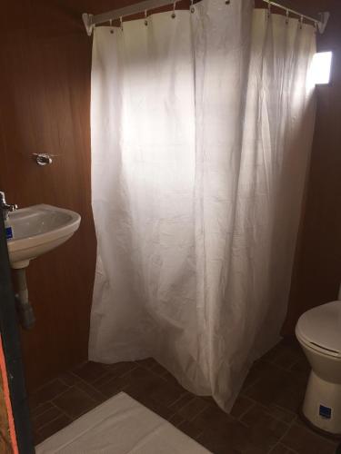 a bathroom with a white shower curtain and a toilet at HOBU MONTAÑA in La Calera