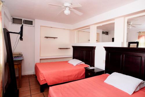 a bedroom with two beds and a ceiling fan at Hotel María Elena in Durango