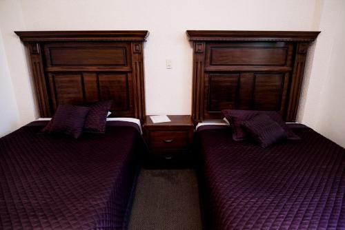 two beds in a room with wooden headboards at Hotel María Elena in Durango
