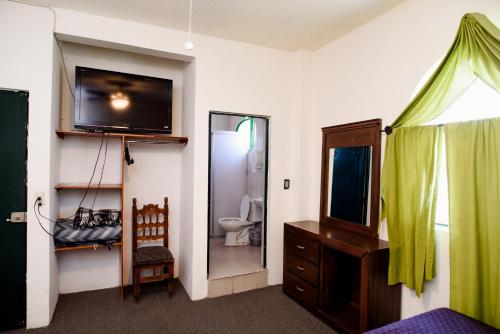 a bedroom with a television and a bathroom with a toilet at Hotel María Elena in Durango
