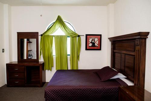 a bedroom with a bed and a window with green curtains at Hotel María Elena in Durango