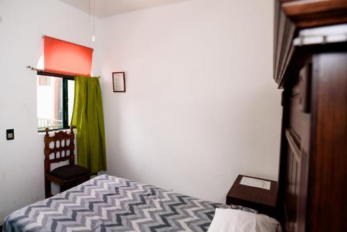 a bedroom with a bed and a chair and a window at Hotel María Elena in Durango