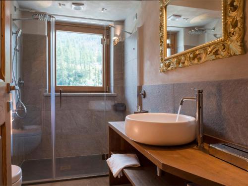 a bathroom with a sink and a shower and a mirror at 3 Chalets Aparthotel in Breuil-Cervinia